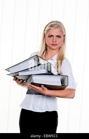 junge Frau mit Haufen Arbeit Stockfoto