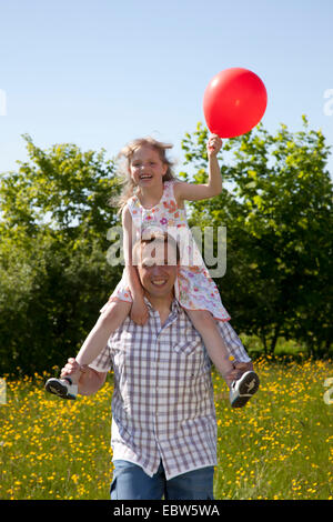 Vater mit seiner kleinen Tochter auf den Schultern in einer Blumenwiese, Deutschland Stockfoto