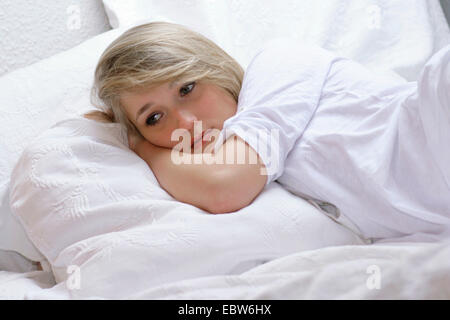 Junge, blonde Frau im Bett liegend Stockfoto