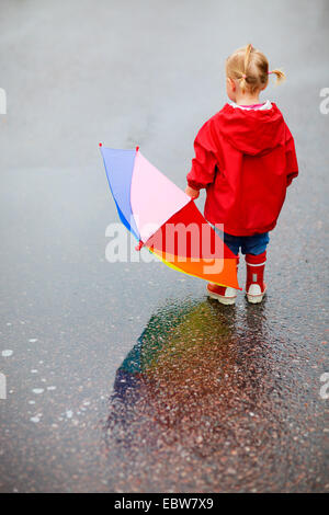 Ansicht von hinten ein kleines Mädchen mit einem Regenschirm Stockfoto