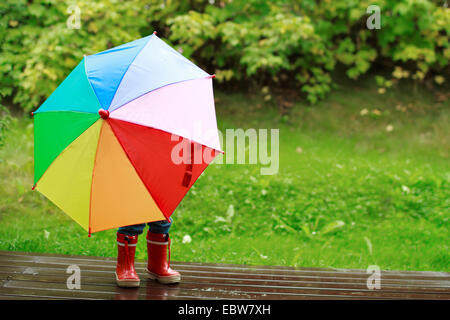 kleines Mädchen versteckt sich hinter einem Regenschirm Stockfoto