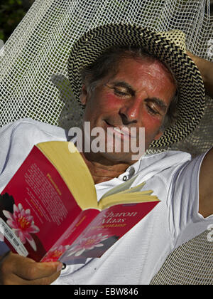 Sonnenbrand, senior in der Hängematte liegen und ein Buch zu lesen Stockfoto