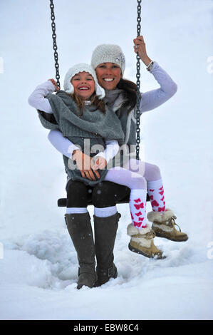 Mutter und Tochter auf Wippe im Schnee Stockfoto