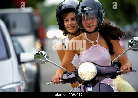 zwei attraktive junge Frauen reiten auf Motorroller Stockfoto