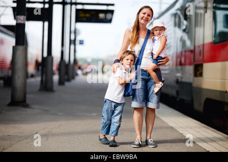 eine junge Mutter mit ihren beiden Kindern warten auf Zug Stockfoto