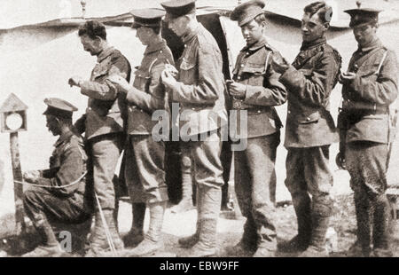 Soldaten des Ersten Weltkriegs synchronisieren ihre Uhren mit einer Uhr, die auf einem Posten im Lager montiert ist. Dies war von entscheidender Bedeutung, um Einstimmigkeit in der Bewegung und perfekte Zusammenarbeit vor einem Angriff zu erreichen. Stockfoto