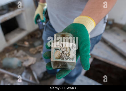 Mann mit Glas mit Babynahrung im alten Holzhaus in Wüstung Stechanka, Sperrzone von Tschernobyl, Ukraine Stockfoto