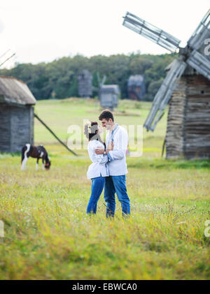 Junges Paar in der ukrainischen traditionellen Hemden auf dem Feld, alte Windmühlen im Hintergrund Stockfoto