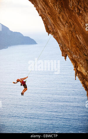 Weibliche Kletterer von einer Klippe fallen, beim Schwierigkeitsklettern Stockfoto