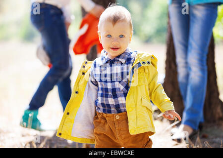 Kleinkind-Boy am hellen Tag im Herbst, mit unscharfen Erwachsene im Hintergrund Stockfoto