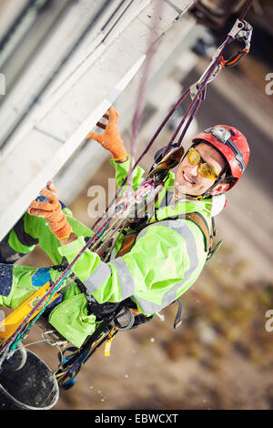 Industriekletterer platzieren eine Polyfoam Blatt Dämmung an der Wand eines Gebäudes Stockfoto