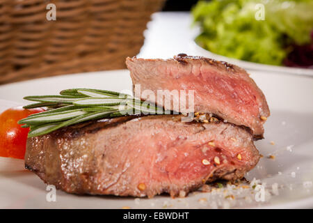 Saftige Rindersteak mit mittlerer selten durch anzuzeigenden das zarte Fleisch in Scheiben geschnitten und gewürzt mit Gewürzen und frischen Rosmarin, clo Stockfoto