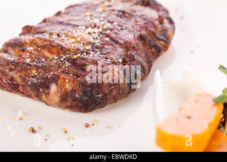 Lecker gegrilltes Rindersteak mit einem gezwirbelten Stück Butter und ein Zweig frischer Rosmarin garniert und serviert auf einem weißen Teller, enge u Stockfoto