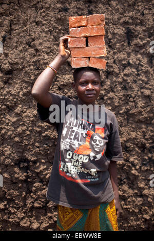 Portrait eines jungen tragen einen Stapel von Steinen auf dem Kopf die gebildet von Schlamm vor Ort und in einem traditionellen Ofen verbrannt Burundi, Kabezi, Kabezi Stockfoto