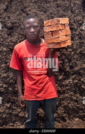 Bildnis eines Knaben mit einem Stapel von Bricks die gebildet von Schlamm vor Ort und in einem traditionellen Ofen verbrannt Burundi, Kabezi, Kabezi Stockfoto