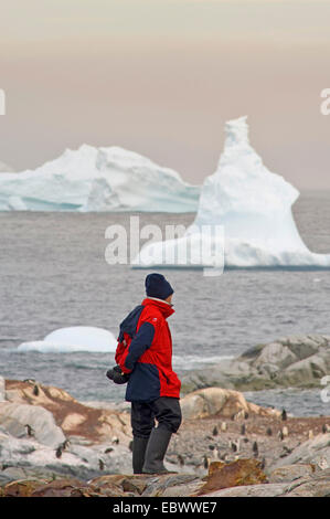 Touristen auf Petermann Island, Eisberg im Hintergrund, Antarktis Stockfoto