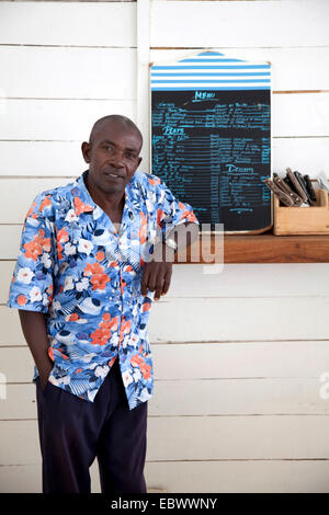 Mann, der an einer Theke mit Besteck und Menü, Burundi, Bujumbura Mairie, Bujumbura Stockfoto