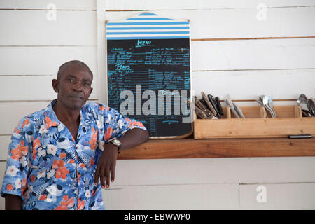 Mann, der an einer Theke mit Besteck und Menü, Burundi, Bujumbura Mairie, Bujumbura Stockfoto