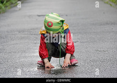 kleines Mädchen, zwei Jahre alt, spielen in einer Pfütze, Deutschland Stockfoto