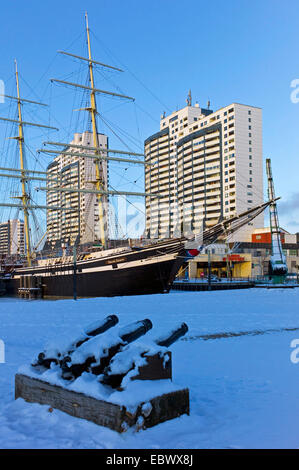 Schnee bedeckt die Kanonen des deutschen Schiffahrtsmuseum, Segeln von Schiff und Columbus Center im Hintergrund, Deutschland, Bremerhaven Stockfoto