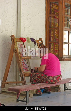 Frau sitzt konzentriert sich auf ihre Arbeit in einem Teppich Workshop, Türkei, West-Anatolien Stockfoto