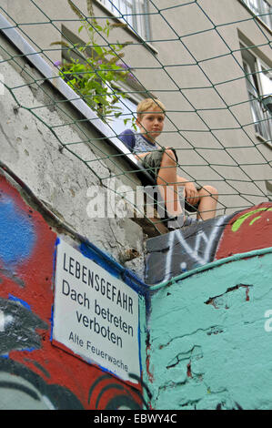 neun Jahre alter Junge sitzt auf verbotene Dach, Deutschland, Köln Stockfoto