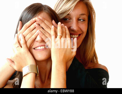 eine Blondine und eine Brünette junge Frauen spielen peekaboo Stockfoto