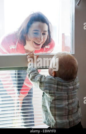 kleine Jungen und Mutter gerade durch Fensterglas Stockfoto