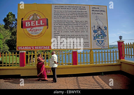 Touristen-paar steht vor ein hoch Board-Schild mit Informationen über eine der Quellen des Flusses Nil, Uganda, Jinja Stockfoto
