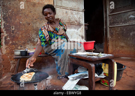 Frau ist ein Chapati gemacht Mais Mehl auf einem Charcole-Ofen vor ein einfaches Haus, Uganda, Jinja genannt Brotbacken Stockfoto