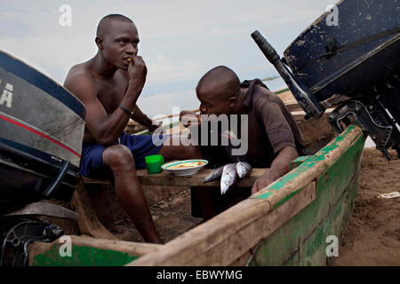 junge Fischer sitzen in einem Boot auf dem Sandstrand nehmen ihr Frühstück nach einer durchzechten Nacht Arbeit, Burundi, Nyanza Lac, Mvugo, Nyanza Lac Stockfoto