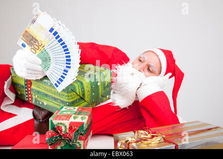 Santa Claus mit Geld und Geschenken Stockfoto