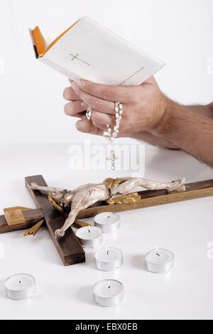 Bibel in der Hand eines Mannes, christliche Dinge auf dem Schreibtisch Stockfoto