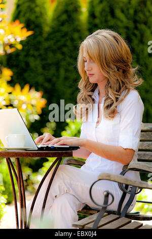 Frau mit Laptop im Garten Stockfoto
