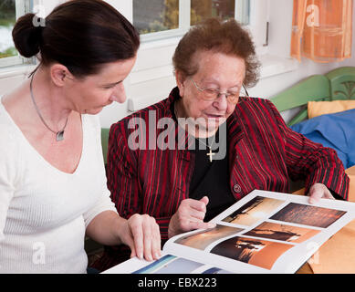 alte Frau Schriftrollen in einem Fotoalbum zusammen mit ihrer Tochter Stockfoto