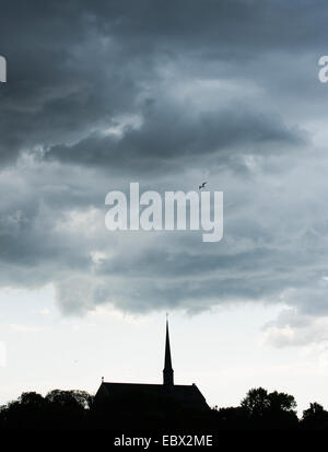 Vogel fliegt über Kirche und Himmel voller Wolken. Abtei von Vadstena, Schweden. Stockfoto