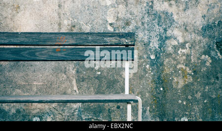 Leere Holzbank mit roten Handabdruck vor verwitterte Steinmauer. Stockfoto