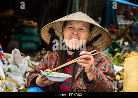 Vietnamesische Dame lächelt in die Kamera, die ihr Essen. Stockfoto