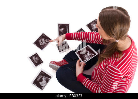 Schwangere junge Frau sitzt auf dem Boden gespannt beobachten Ultraschall Bilder ihres Kindes Stockfoto