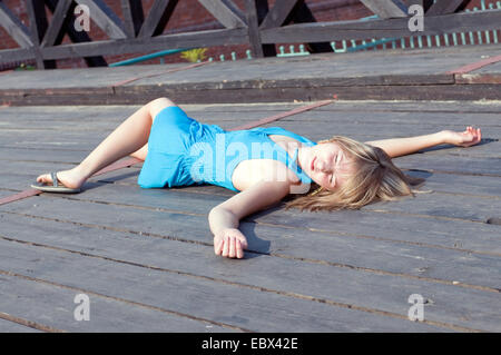Blonde junge Frau, die auf hölzernen Fußboden schlafen liegen Stockfoto