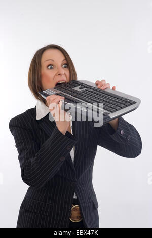 Business Frau beißt in Tastatur Stockfoto
