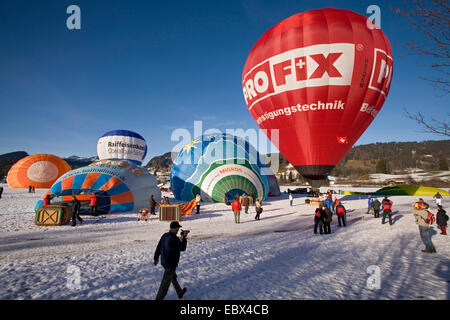 Heißluft-Ballon-Festival auf einem Schneefeld mit mehreren Ballons in Vorbereitung für den Start und viele Zuschauer, Oberstdorf, Allgäu, Bayern, Deutschland Stockfoto