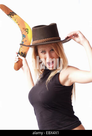 langhaarige blonde junge Frau trägt einen schwarzen Hut mit breiter Krempe und Top erreicht wieder für einen Bumerang zu werfen Stockfoto