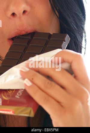 junge Frau in einem Schokoriegel beißen Stockfoto