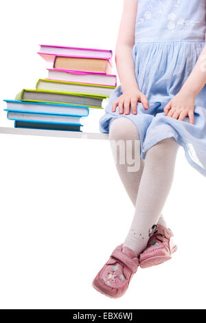 Kleines Mädchen mit Büchern sitzen auf einer Bank Stockfoto