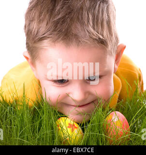 Süsser Boy auf der Suche nach frischen grünen Gras versteckt Ostereier Stockfoto