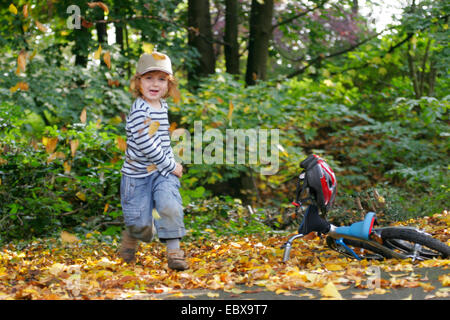 kleiner Junge Autmn Laub wegwerfen Stockfoto