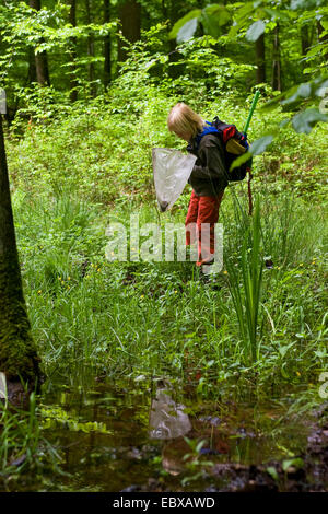 Kind mit einem Sprung net an einem Waldteich Stockfoto