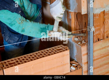 Arbeiter mit Meißel an einer Innenwand in Hohlblocksteine aus Backstein Stockfoto