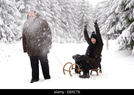 Frau und Mann, Winterurlaub, Frau sitzen auf Schlitten Stockfoto